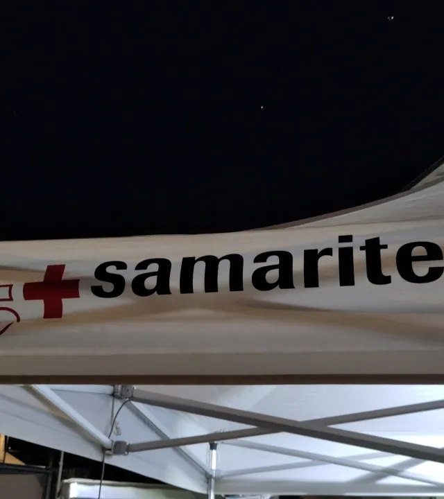 Das obere Ende eines Samariter-Zelters bei Nacht mit dem Samariter-Logo